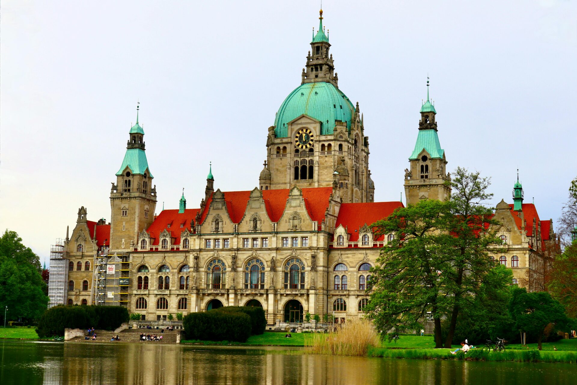 Rathaus Hannover, großes Gebäude im Hintergrund, im Vordergrund ein kleiner Park und See vor dem großen Gebäude.