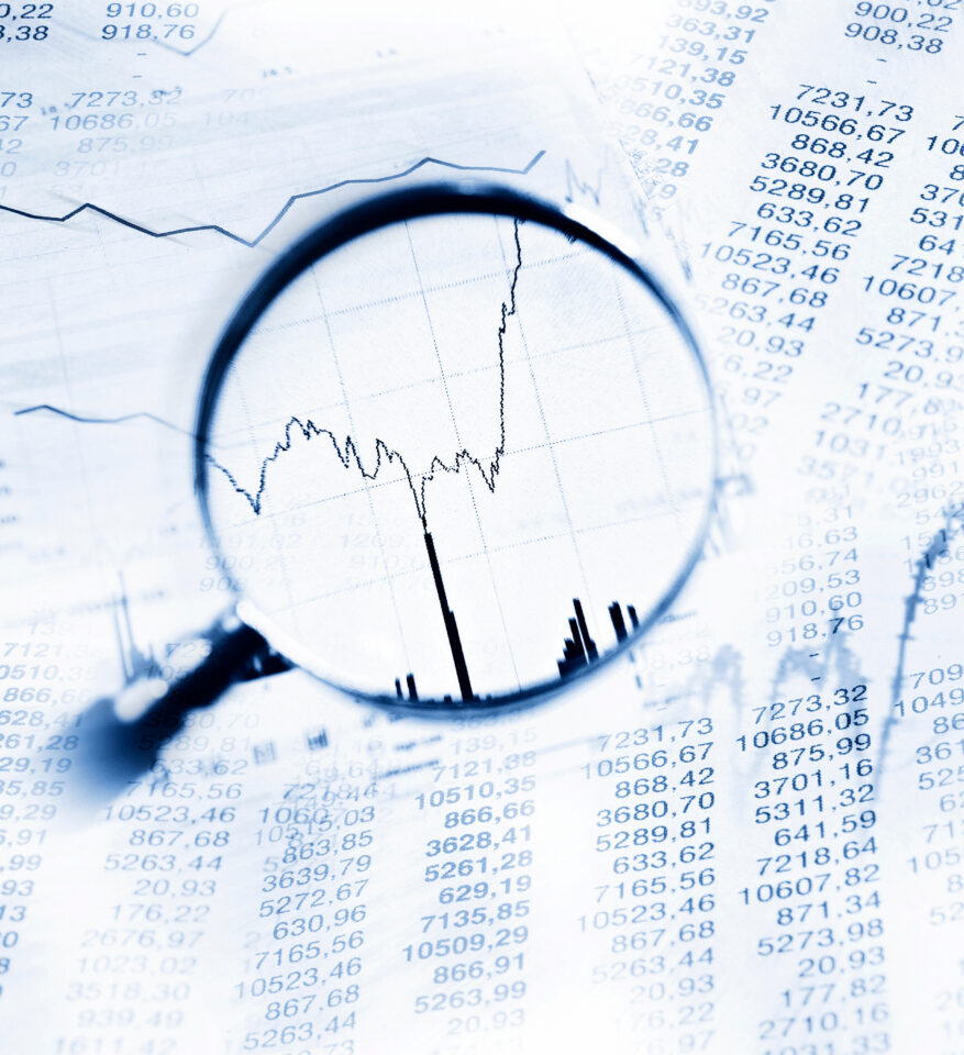 Papier mit vielen Zahlen und einer Lupe