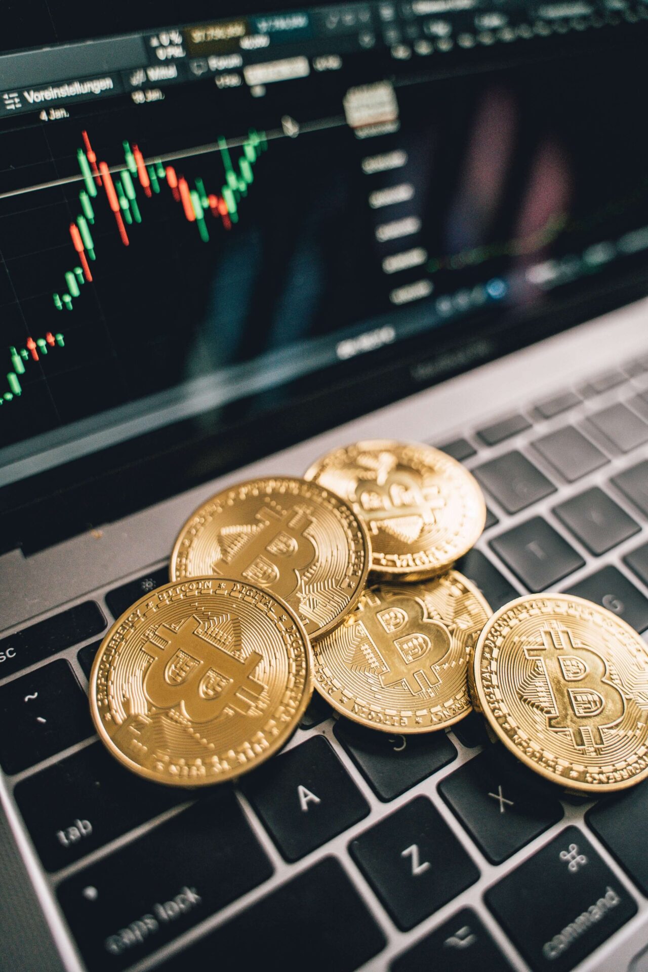 Geöffnetes Macbook und auf Tastatur liegen Bitcoin Münzen
